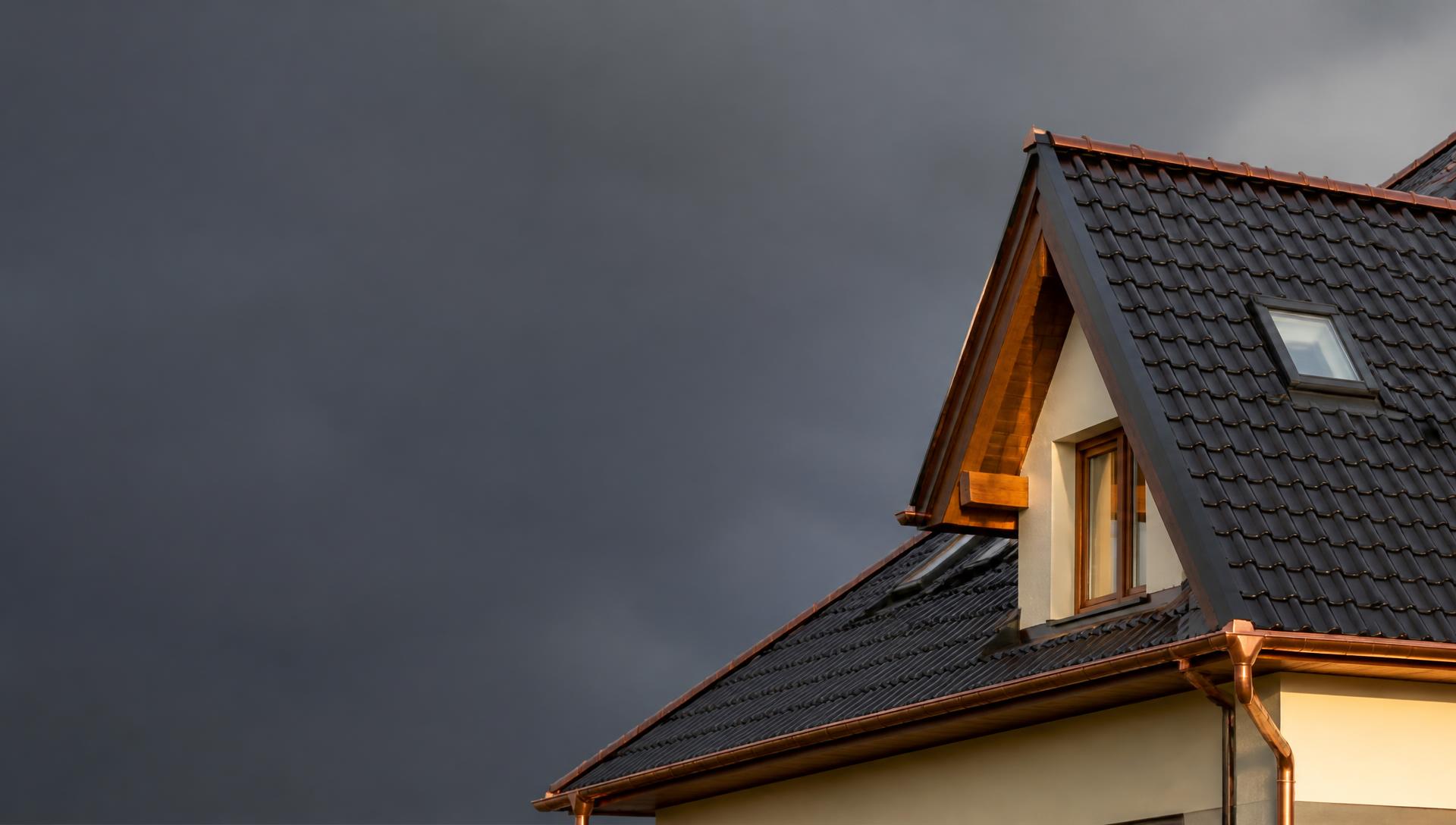 Dokončená střecha rodinného domu s antracitovou krytinou a měděnými klempířskými prvky